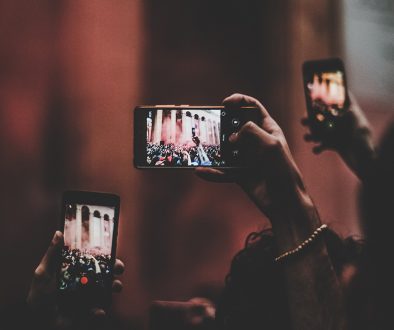 photo of multiple people holding up phones to take a photo.